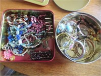 Two tins of bracelets and necklaces