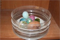 Lot of stone and wooden eggs in glass dish