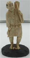 Ivory carving of a man holding a tool over his sho