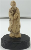 Ivory carving of a man holding a gourd on a hardwo