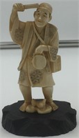 Ivory carving of a man holding a basket and a smal