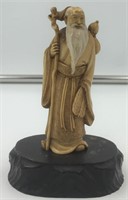 Old ivory carving of an elderly man holding a walk