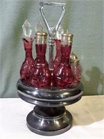 Cranberry glass condiment set with glass stoppers.
