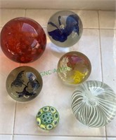 6 glass paperweights - different colors - one with