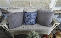 White wicker settee with cushions and pillows