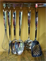 SIX STAINLESS UTENSILS, PLUS HANGER