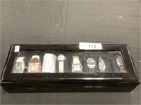 Seven watches in watch display case.