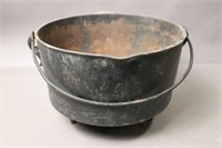 THREE FOOTED CAST POT WITH HANDLE AND SPOUT