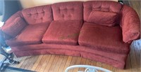 Burgundy velvet sofa with a low back, rounded.