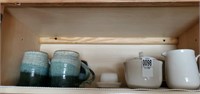 Shelf of coffee mugs,  creamer , sugar etc