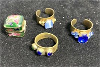 Three antique brass rings and enameled pill box