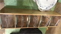 Wood box shelf with 5 thick glass containers.