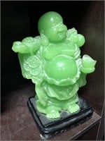 Green plastic Buddha statue with black base