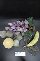 Three hard stone carved fruits: banana, purple gra