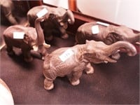 Four metal elephants, all with trunks up