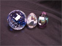 Three colorful paperweights: two are egg-shaped,