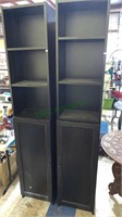 2 black tall skinny shelf units with cabinet