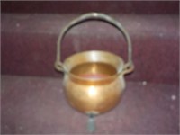 Hammered copper footed pot has handle