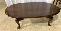 Oval wood coffee table with cabriole legs.