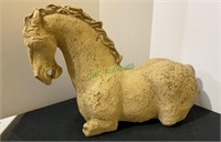 Ceramic horse statue kneeling on the ground.