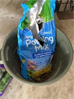 Trash can partial bag of potting soil and weed and