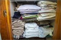 Two shelves of assorted bed linens