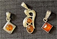 THREE PRETTY AMBER AND STERLING SILVER PENDANTS