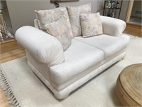 Plush white upholstered loveseat with pillows