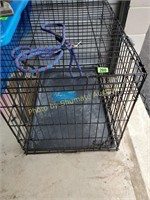Large black metal dog crate with leash