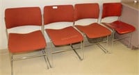 Four orange stacking break room chairs