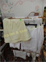 GROUP OF ASSORTED LINENS ON VINTAGE SEWING RACK.