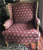 Red flowered wing chair with wood trim