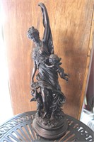 Metal decorative statue of woman with two angels.