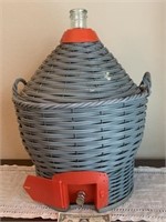 Large glass wine bottle in basket with dispenser