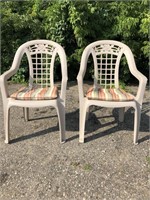 Pair of plastic patio chairs with cushions