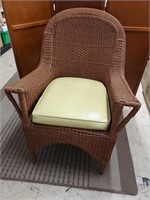 Wicker patio chair with seat cushion.