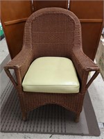 Wicker patio chair with seat cushion.