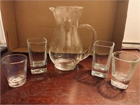 Four shot glasses and a pitcher