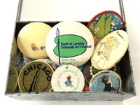Tin container of assorted buttons, keychains, etc.