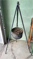 Iron kettle planter on a stand with a crack down