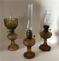 Three miniature amber glass oil lamps (6” to 8”).