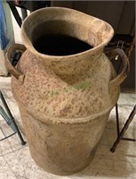 Old rusty milk can with two handles and no lid.