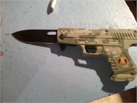 Folding knife in the shape of a camo handgun v