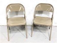 Two tan metal folding chairs