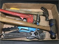 A pair of hammers, a pipe wrench, wire stripper