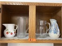 Shelf of 4 glass pitchers.
