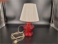 Ruby red glass table lamp with plastic shade.