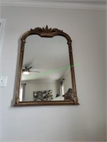 Large ornate wall mirror in gold frame.