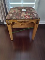 Wooden stool with carvings and fabric top.