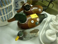 Two carved wooden ducks along with another.